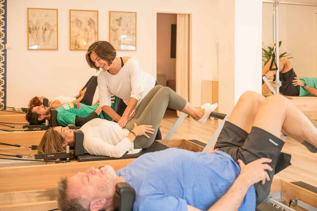 Profesora de pilates corrigiendo ejercicios a los alumnos