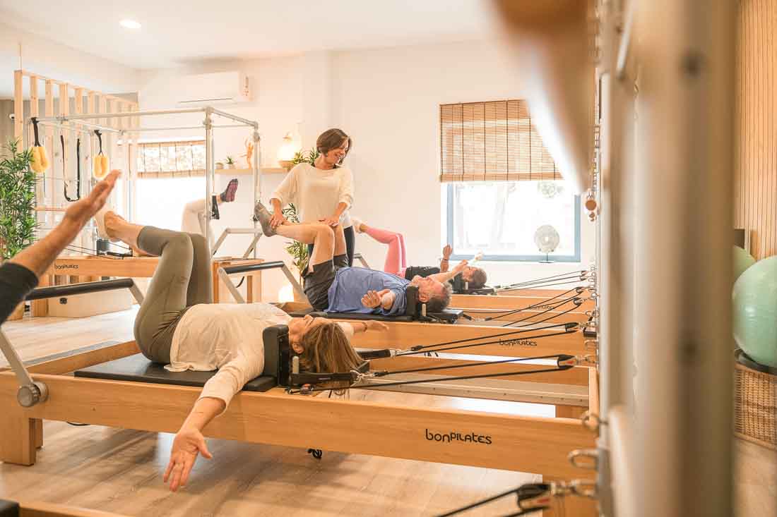 Profesora de pilates corrigiendo postura a un alumno