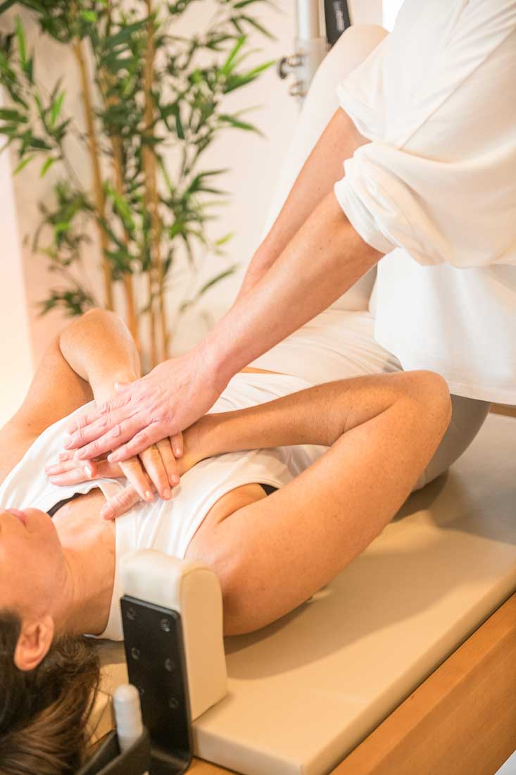 Manos corrigiendo ejercicio de pilates